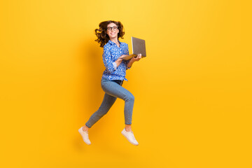 Fototapeta na wymiar Full body profile photo of cheerful active lady jumping rush use wireless netbook isolated on yellow color background