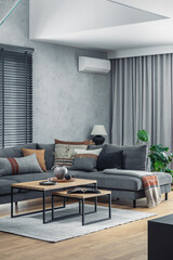 Creative composition of elegant living room interior with grey corner sofa, coffee table and stylish personal accessories. Modern home decor. Panoramic windows. Template.