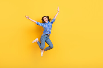 Fototapeta na wymiar Full size photo of cheerful overjoyed girl jumping raise hands empty space isolated on yellow color background