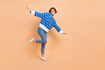 Fototapeta na wymiar Full length photo of charming impressed woman dressed striped sweater having fun empty space isolated beige color background