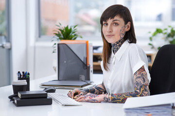 Exercising self-expression. A shot of a tattooed businesswoman sitting at her desk in her office.