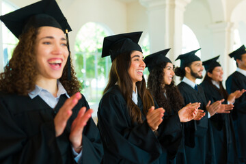 Excited graduates clapping celebrating on their graduation ceremony