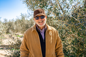 Elderly man smiling outdoors in nature looking to camera.