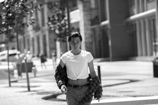 Young dark-haired guy walking along summer city street
