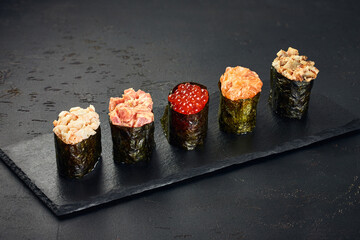 Set of Gunkan Maki Sushi with different types of fish (salmon, scallop, perch, eel, shrimp) and caviar on black background. Traditional Japanese cuisine © Irina Burakova