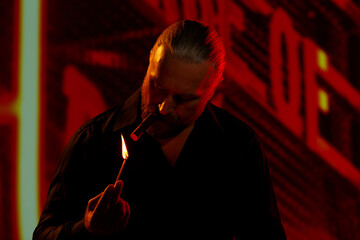 Focused man holding lit match and lighting cigar in night city