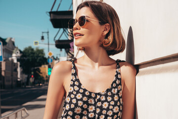 Young beautiful smiling hipster woman in trendy summer overalls clothes. Sexy carefree model posing on the street background at sunset. Positive brunette female. Cheerful and happy. In sunglasses © halayalex