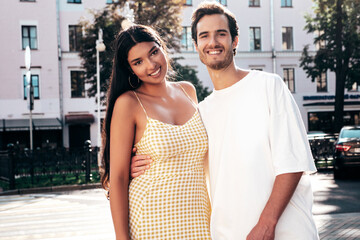 Smiling beautiful woman and her handsome boyfriend. Happy cheerful family. Sexy couple posing in the street at sunrise. During romantic date at sunny summer day outdoors. Looking at each other