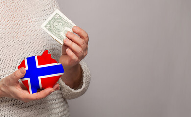 Flag of Norway on money bank in Norwegian woman hands. Dotations, pension fund, poverty, wealth, retirement concept