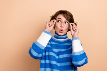 Photo of excited funky woman dressed striped sweater arms eyewear looking empty space isolated beige color background