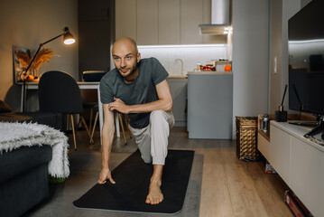 A man is doing physical exercises on a mat while working out at home
