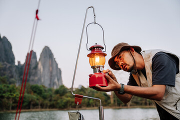 Asian man lanterns are lit Vintage Kerosene lamp burning with a soft glow light in an dark forest wood. Light in the darkness. Outdoor Camping Concept.