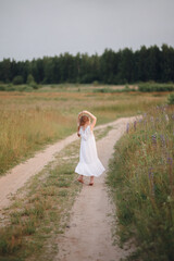 The girl runs along the forest road. Summer evening field and child