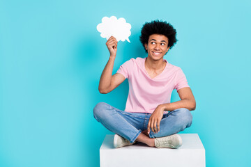 Full length body photo of youth smart guy hold paper bubble opinion cloud thoughtful sit white cube...