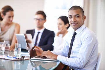 Hes got technology on his side. Portrait of an happy businessman using his laptop in the office.