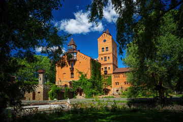 Fototapeta premium Ancient castle green trees against a background of blue sky and white clouds