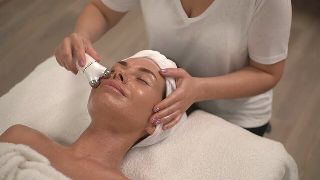 the master performs the procedure using a microcurrent device for the face. slow motion video. High quality Full HD video recording