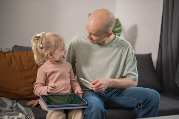 People with cochlear implant system. Kid study to hear with her father, learning with video on...