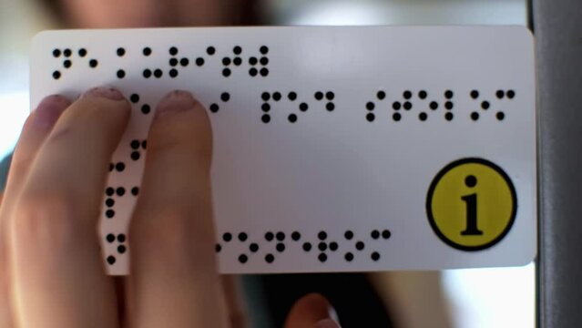 Fingers touching relief of points Braille text plate. Information for person with blindness on the train door. Assistance and care for people with poor vision, accessibility of transport concept.