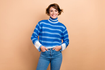 Photo of carefree charming lady wear blue pullover smiling hands arms pockets isolated beige color background