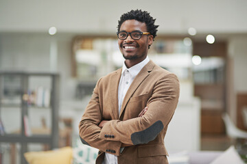 Looking sharp and feeling great. Cropped portrait of a confident young businessman standing with his arms folded in his office.