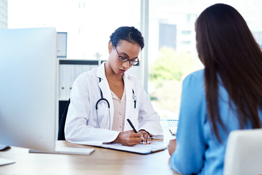 Im Going To Write A Referral For You. Shot Of A Young Doctor Having A Discussion With A Patient In Her Consulting Room.