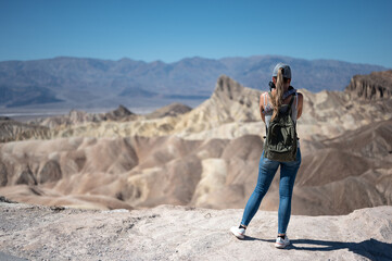 Naklejka premium a young girl with her back turned to take pictures of the desert landscape in Death Valley Desert