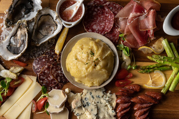 Appetizers with different cheeses, sausage, ham, smash potato, tapas, and oysters for buffet party. Close-up.
