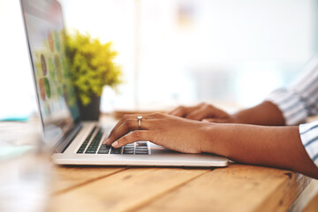 Fototapeta premium Starting a blog is always a good idea. Cropped shot of an unrecognizable young woman using her laptop on a wooden table.
