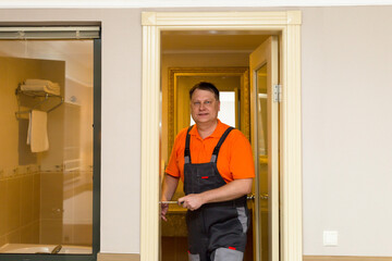 Man work clothes repairing the lock on the door.