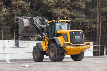 Skid steer loader loading a truck with waste material transferred for further sorting, treatment,...