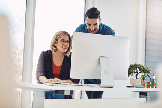 Putting Technology To Work. Shot Of A Young Man And Woman Using A Computer Together In A Modern Office.