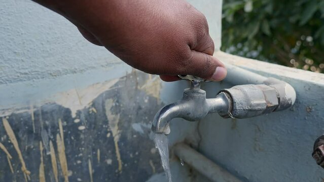 A close up of turning on the tap water with hand