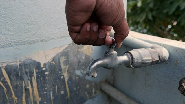 A closeup of turning off the tap water with a hand