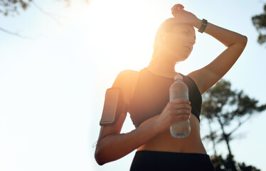 You dont always need a gym to break a sweat. Shot of a fit young woman stopping for a drink of water during a run outdoors. - Powered by Adobe