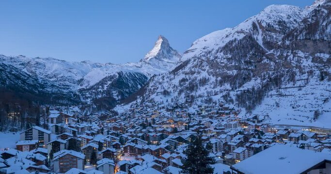 4K Time lapse of Zermatt city Valley famous travel ski resort and iconic Matterhorn peak at dawn in Swiss alps, Switzerland. The snow covered village and church in Canton Valais in winter Timelapse.