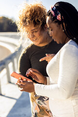 Two young plus size women resting after running and looking at phone.