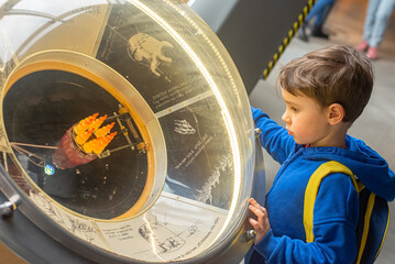 Zaciekawiony chłopiec w Centrum Nauki Kopernik ogląda i poznaje eksponaty. Wiedza, edukacja dzieci. © malgo_walko