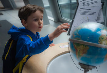 Five year old cute boy in science world carefully observing exponents in museum. Curiosity and children's knowledge concept.