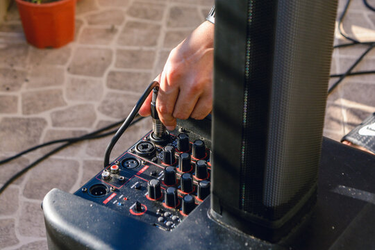male hand installing sound cable in speaker set.