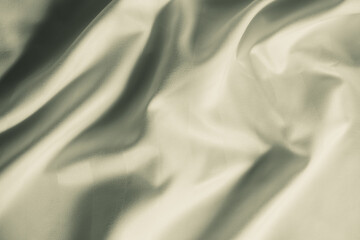 Satin crumpled fabric of light olive color, top view. Natural bed linen, sheets, abstract background of luxury fabric, wavy folds