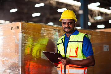 Male factory warehouse worker using checklist bord in storehouse for import export business.