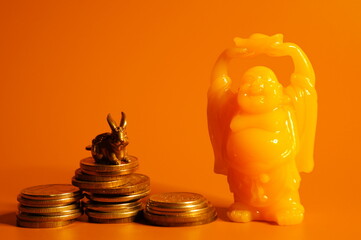 Rabbit and Buddha figurine with coins on a bright colored background. The symbol of Feng shui....
