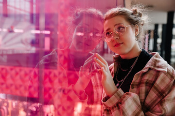 portrait of young hipster girl against pink glass background