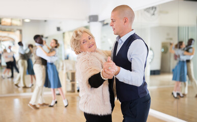 Man and mature woman learning to dance classical ballroom dance