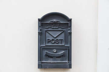 Close-up of a black metal mailbox on a white stone building