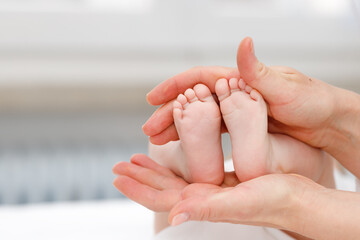 Close up of baby's foots in mother hands. Childhood and baby care concept