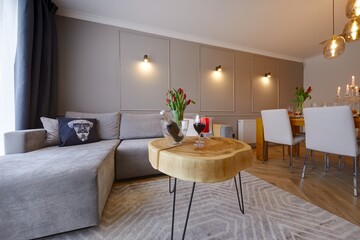Fototapeta Przytulny apartament z wygidą sofą, na pierwszysm planie stolik kawowy z butelką wina i kieliszkami obraz