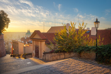 Beautiful view of new castle stairs in the old town with a historic street lamp in the glow of the sunrise. Autumn in the city of Prague, the capital of the Czech Republic