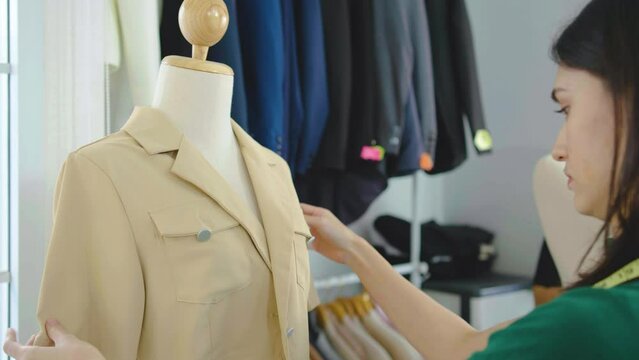 Woman designer using tape measure measuring Measure the length and width of the shirt in workshop studio, Measure the size and recheck the sewing before sending to customers in a tailoring shop